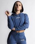 Woman wearing blue cropped LYFTLYFE hoodie with drawstring, front-facing pose.