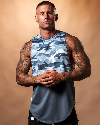 Blue camouflage sleeveless shirt with a white brand logo on a light gray background