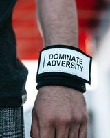 Close-up of wrist wearing wrap with "DOMINATE ADVERSITY" patch facing forward.