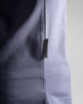 Close-up of the Dominate Adversity tag on the Contour Tee in purple, highlighting premium craftsmanship and branding.