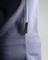 Close-up of the Dominate Adversity tag on the Contour Tee in purple, highlighting premium craftsmanship and branding.