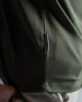 Close-up of the Dominate Adversity tag on the Contour Tee in green, highlighting premium craftsmanship and branding.