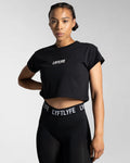 Left side view of the black Drill Women’s Crop T-shirt, showcasing its fitted cut, soft-stretch fabric, and moisture-wicking properties.
