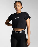 Left side view of the black Drill Women’s Crop T-shirt, showcasing its fitted cut, soft-stretch fabric, and moisture-wicking properties.
