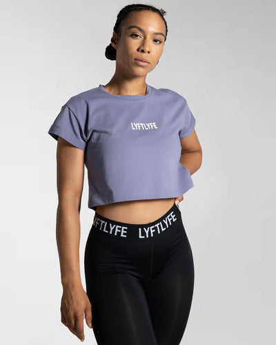 Drill Women’s Crop T-shirt in purple, showcasing its fitted cut, soft-stretch fabric, and moisture-wicking properties.