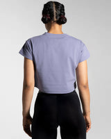 Women’s cropped Drill Tee in purple, displayed from the back, featuring a soft crew neckline and premium cover-stitching.
