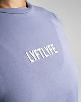 Close-up of the white Lyftlyfe logo on the purple Women’s Drill Crop Tee, crafted with precision and high-quality materials.