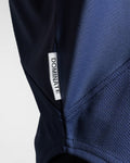 Detailed shot of Dominate Adversity tag stitched into the curved hem of the lightweight performance tank in blue. 