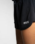 3D rubberized LYFTLYFE logo close-up on black athletic shorts.