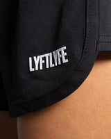 Close-up of logo placement on left thigh of black HIIT women’s shorts.