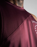 Close-up of reinforced seams and stretchable tri-blend fabric on sleeveless tank top in dark wine color. 