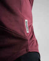 Close-up of Dominate Adversity side tag on Men’s Dominance Cut Sleeve in red wine color, stitched for lasting durability.