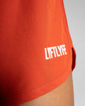 3D rubberized LYFTLYFE logo close-up on red athletic shorts.