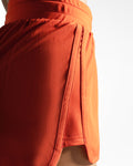 Detail of curved hem and stitching for full mobility and airflow of women's red gym shorts. 