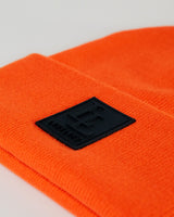 Zoomed-in detail of black LL patch on bright orange LYFTLYFE beanie.