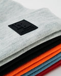 Pile of LYFTLYFE beanies in multiple colors with focus on black logo patches.