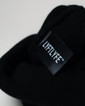 Detail of black LYFTLYFE fabric tag stitched inside black beanie.
