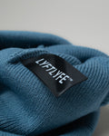 Detail of black LYFTLYFE fabric tag stitched inside blue beanie.