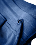 Extreme close-up of LYFTLYFE logo cap and stitching on drawstring on the blue women's joggers. 