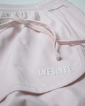 Close-up of logo placement on left side of light pink HIIT women’s shorts.