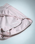 3D rubberized LYFTLYFE logo close-up on athletic shorts in light pink. 