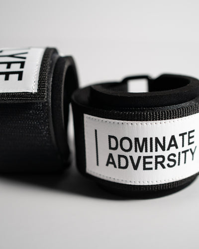 Pair of LYFT wrist wraps stacked, showing "DOMINATE ADVERSITY" and "LYFTLYFE" branding.