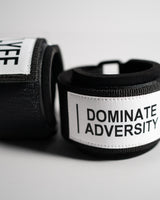 Angled close-up of LYFT wrist wraps, focusing on the "DOMINATE ADVERSITY" patch.