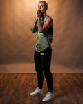 Women’s sleeveless tank top in green camo, displayed from the side, highlighting its curved hem and durable triple-blend fabric.