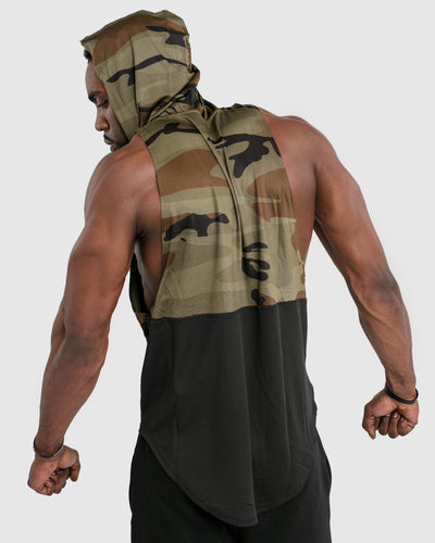 Mens sleeveless hoodie made with two panels. The top panel is camo, including the hood. The bottom panel is black. 