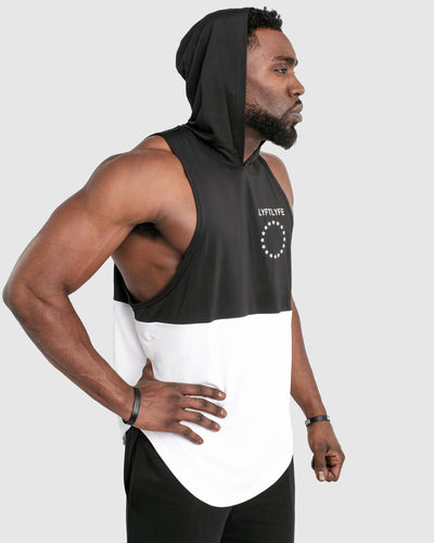 A Mens sleeveless tank top with a hood. Made with two panels - black on the top and white on the bottom with a black hood.